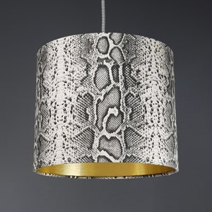 May include: A black and white snake skin patterned lampshade with a gold trim.