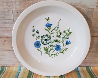 May include: White pie plate with a floral design featuring blue and green flowers.