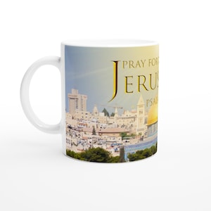 Pode incluir: Caneca de cerâmica branca com uma imagem colorida de Jerusalém, incluindo a Cúpula da Rocha, e o texto dourado "PRAY FOR JERUSALEM". O design apresenta os marcos da cidade.