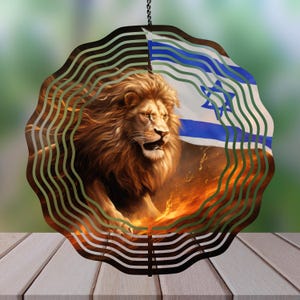 May include: A metal wind spinner with a lion and the Israeli flag. The lion is depicted in a fiery orange and yellow background. The flag is blue and white with a six-pointed star in the center.