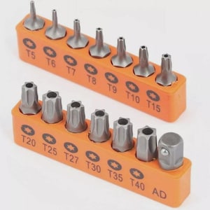 May include: A set of Torx screwdriver bits in an orange holder. The bits are silver and arranged in two rows, labeled with sizes T5 through T40 and AD. The holder has a star-shaped symbol next to each size.