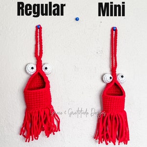 May include: Two crocheted red hanging pockets with white eyes and a fringe. The pocket on the left is labeled "Regular" and the pocket on the right is labeled "Mini".