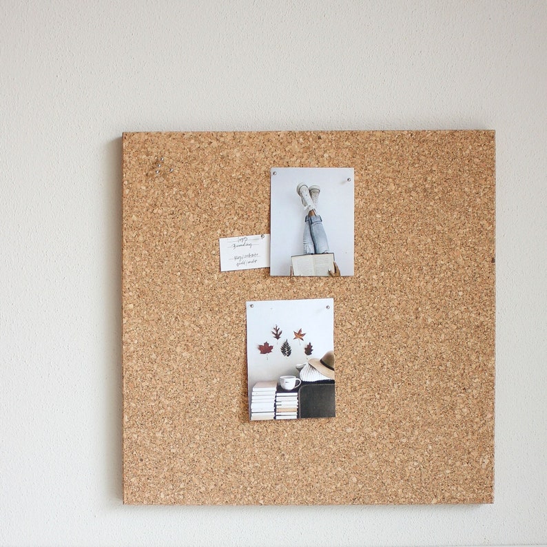May include: A corkboard with three photos pinned to it. The top photo shows a person's legs in the air with their shoes showing. The middle photo shows a handwritten note. The bottom photo shows a stack of books, a mug, and some fall leaves.