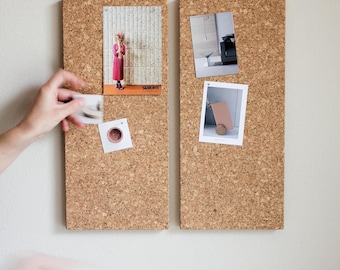 May include: Two cork boards with various images pinned to them. The images include a woman in a pink dress, a room with furniture, and a small cart. The boards are mounted on a white wall.