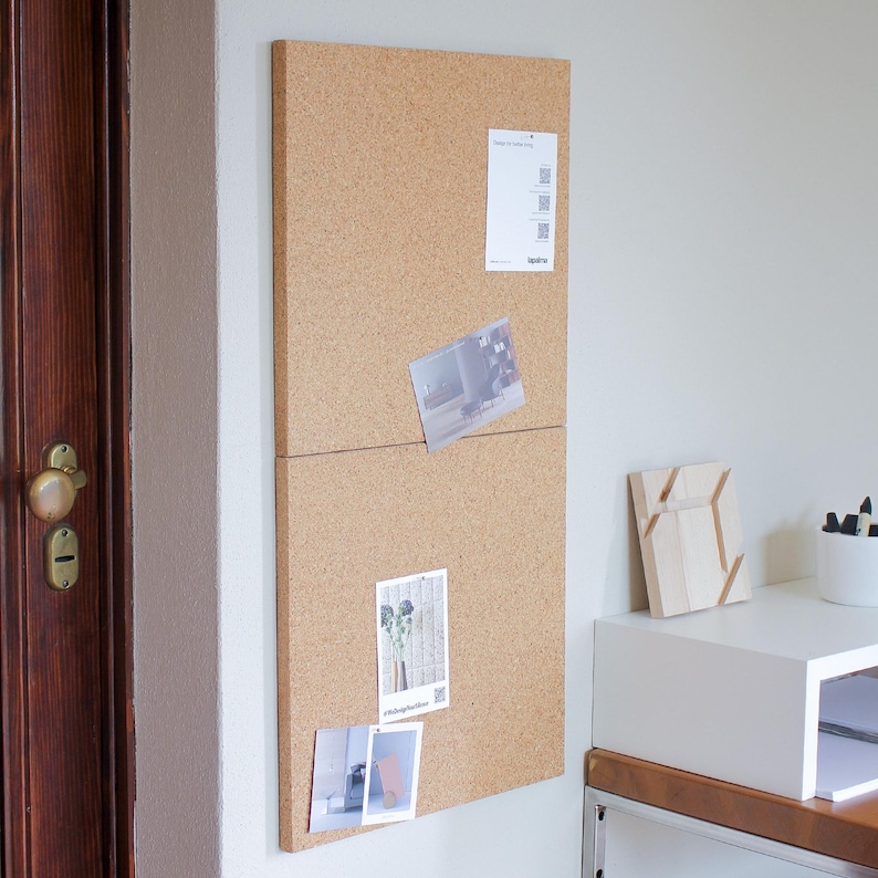 May include: A corkboard with a light brown finish and a horizontal divider. The corkboard has several photos and a small card with a QR code pinned to it.