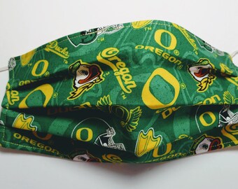 May include: Green face mask with a repeated pattern of the University of Oregon's logo, including the letter 'O', a duck mascot, and the word 'Oregon'.