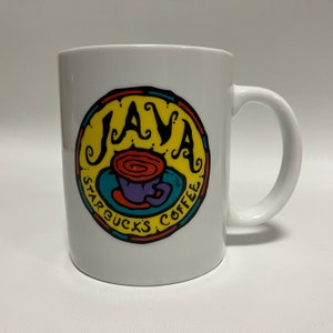 May include: White ceramic coffee mug with a colorful "JAVA STARBUCKS COFFEE" logo. The logo features a yellow background with the word "JAVA" in black, a red and brown coffee swirl, and a purple coffee cup.