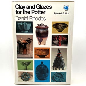 May include: A book cover titled "Clay and Glazes for the Potter" by Daniel Rhodes. The cover features a grid of ceramic pieces in various shapes, colors, and textures, including bowls, vases, and decorative objects. The book is a revised edition.