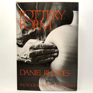 May include: A book cover with the title "POTTERY FORM" in orange letters. The cover features a black and white image of hands shaping a clay pot. The author's name, Daniel Rhodes, is also in orange.
