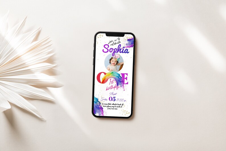 May include: A colorful invitation for a first birthday party. The invitation features a rainbow with the number "one" in large letters. The invitation also includes a photo of a young girl and the text "Join us to celebrate Sophia's 1st birthday."