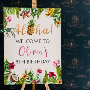 May include: A welcome sign for a 5th birthday party with a tropical theme. The sign features a pineapple, flowers, and leaves in shades of green, yellow, pink, and red. The text on the sign reads "Aloha! Welcome to Olivia's 5th Birthday."