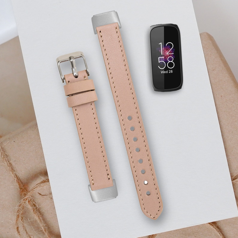 May include: Two light pink leather watch bands with silver buckles. The watch band on the left has a buckle on the bottom and the watch band on the right has a buckle on the top. The watch band on the right has a pointed end.