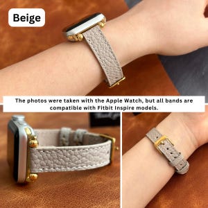May include: Beige leather watch band with gold hardware. The band is shown on a wrist and on a table. The photos were taken with the Apple Watch, but all bands are compatible with Fitbit Inspire models.