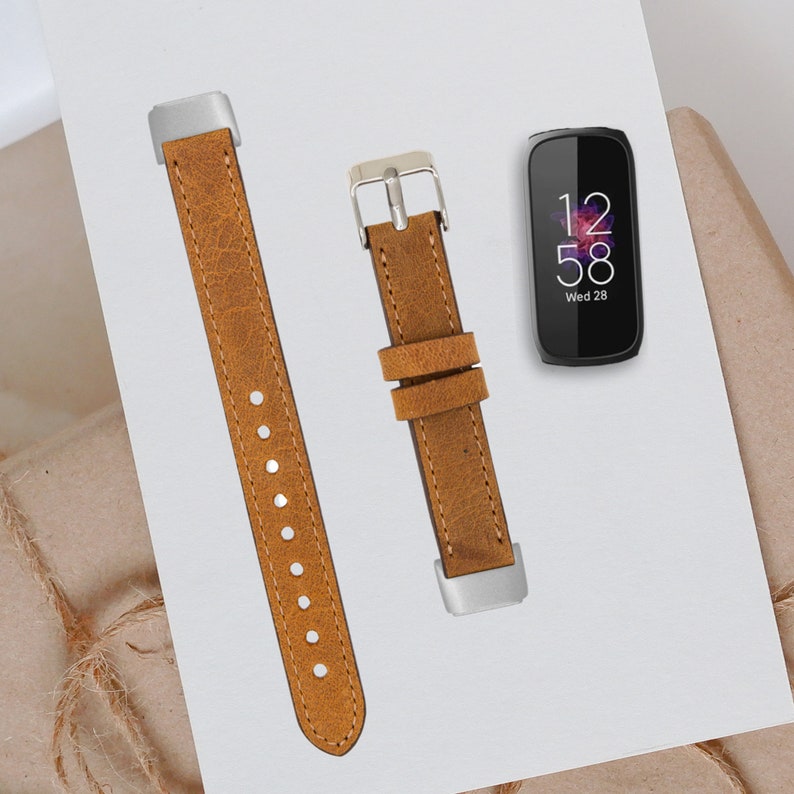 May include: Two brown leather watch bands with silver buckles. The watch bands are for a smart watch. The watch face shows the time as 12:58 and the day as Wed 28.