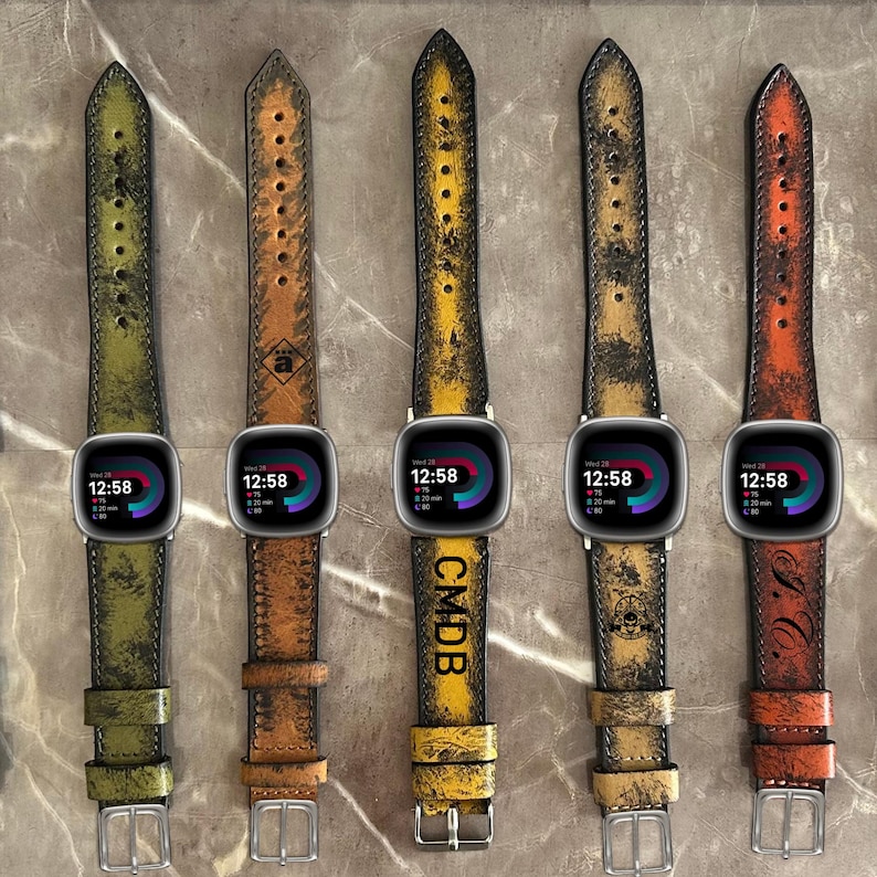 May include: Five different colored leather watch bands with distressed and worn looks. The bands are all for smartwatches and have a black watch face with a digital clock display. The bands are in the colors green, brown, yellow, brown, and orange.
