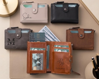 May include: Five bi-fold wallets in beige, black, dark gray, and two shades of brown. Each wallet features a snap-button closure, card slots, and a clear ID window. Some wallets are personalized with names like Sophia, Markus, or initials and a date.