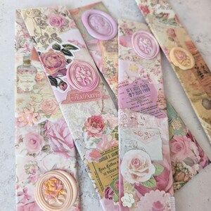 May include: A selection of handcrafted bookmarks with a vintage theme. Each bookmark is a collage of floral designs, paper ephemera, and wax seals. The colour scheme includes soft pinks, creams, and hints of yellow. Some bookmarks feature the text "TEA PARTY".