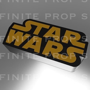 May include: A rectangular sign with the words "STAR WARS" in gold lettering on a black background. The sign has a silver border and is slightly angled, with the text "INFINITE PROP SHOP" repeated in the background.