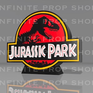 May include: A black and yellow Jurassic Park sign with a red background and a dinosaur silhouette. The words "JURASSIC PARK" are in white, outlined in black. The sign is a prop from the Infinite Prop Shop.