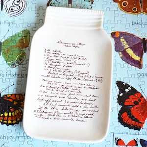 May include: White ceramic dish shaped like a mason jar with a handwritten recipe for Chicken Stew on the front. The recipe includes ingredients like chicken, water, onions, carrots, celery, and butter.