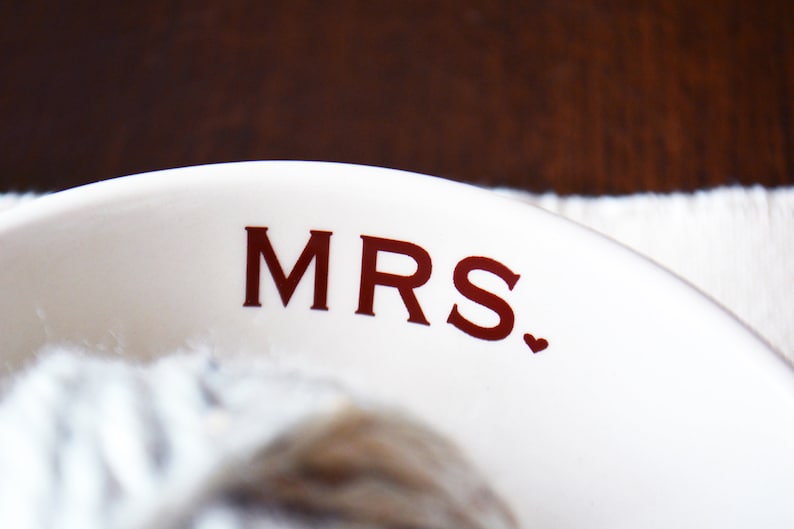 May include: White ceramic bowl with the word "MRS." printed in red lettering with a small red heart.