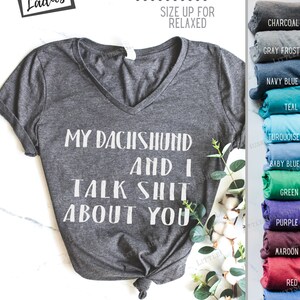 Puede incluir: Una camiseta de cuello en V de color gris jaspeado con el texto "My Dachshund and I Talk Shit About You" impreso en blanco. La camiseta es semi-ajustada y talla peque&ntilde;a, por lo que se recomienda pedir una talla m&aacute;s grande para un ajuste m&aacute;s holgado. La camiseta es s&uacute;per suave y est&aacute; disponible en una variedad de colores.