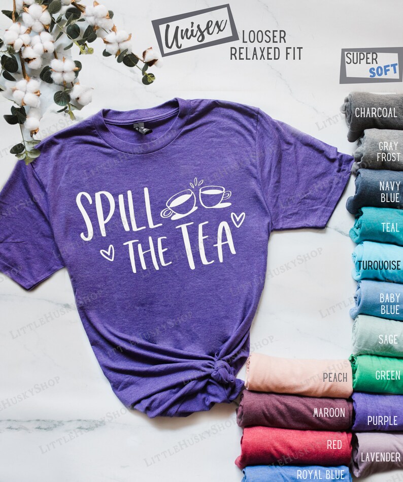 May include: Purple t-shirt with the text "Spill the Tea" and two teacups. The shirt is available in a variety of colors, including charcoal, gray frost, navy blue, teal, turquoise, baby blue, sage, peach, green, maroon, purple, red, royal blue, and lavender.