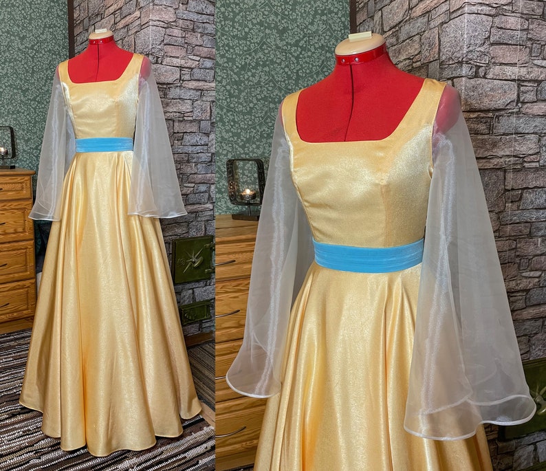 May include: A yellow satin dress with a blue sash and sheer white sleeves. The dress has a square neckline and a full skirt.