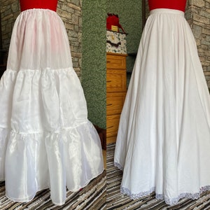 May include: Two white petticoats, one with multiple layers of tulle and the other with a single layer of cotton and lace trim. Both are full-length and have a gathered waist.