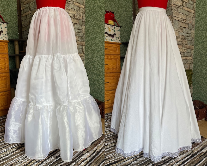 May include: Two white petticoats, one with multiple layers of tulle and the other with a single layer of cotton and lace trim. Both are full-length and have a gathered waist.