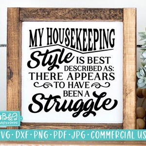 May include: A white sign with a brown wooden frame, featuring the text "My Housekeeping Style is Best Described As: There Appears To Have Been A Struggle".
