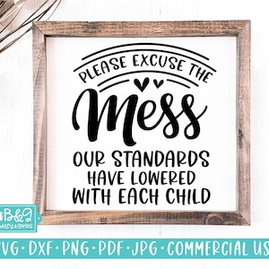 May include: A framed sign with the text "PLEASE EXCUSE THE Mess OUR STANDARDS HAVE LOWERED WITH EACH CHILD" in black lettering. The frame is made of wood. The bottom of the sign has the text "SVG • DXF • PNG • PDF • JPG • COMMERCIAL USE".