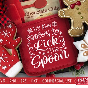 May include: Red oven mitt with the text "Tis the season to lick the spoon" in white. The oven mitt is surrounded by gingerbread cookies and a bag of chocolate chip cookie mix.
