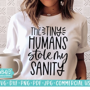 May include: White t-shirt with black text that reads "THE TINY HUMANS stole my SANITY".
