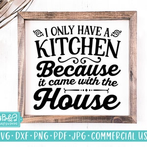Può includere: Un cartello in legno incorniciato con il testo "I only have a kitchen because it came with the house" in lettere nere.