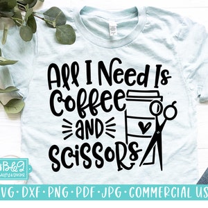 May include: A light blue t-shirt with black text that reads "All I Need Is Coffee And Scissors" with a coffee cup and scissors graphic.