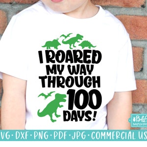 May include: A white t-shirt with a green dinosaur graphic and the text "I ROARED MY WAY THROUGH 100 DAYS!"