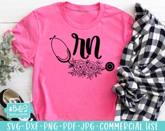 May include: Pink t-shirt with a black design of a stethoscope, flowers, and the word "RN".