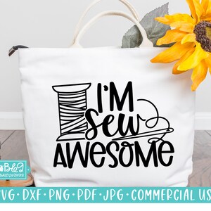 Puede incluir: Una bolsa de tela blanca con un diseño negro que dice "I'm Sew Awesome" con una bobina de hilo y un diseño de aguja e hilo.