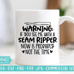 May include: White ceramic mug with a black graphic that reads "WARNING: If you see me with a seam ripper now is probably not the time."  The graphic also includes a black illustration of a seam ripper.