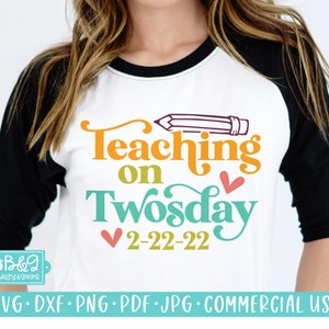 May include: A white and black baseball tee shirt with the text "Teaching on Twosday 2-22-22" in colorful letters. A red pencil with a yellow eraser is drawn above the text.