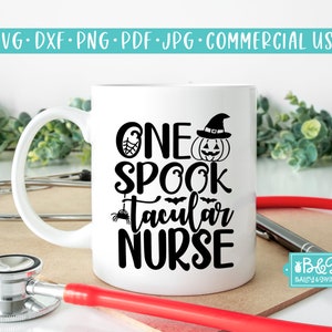 May include: White ceramic mug with a black design that says "One Spooktacular Nurse" with a witch's hat, pumpkin, spider, and bats. The mug is on a wooden surface with a stethoscope and a red medical cord.