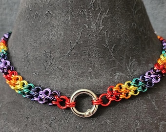 May include: A rainbow-colored chainmail necklace with a silver clasp. The necklace features a vibrant array of colors, including red, orange, yellow, green, blue, and purple. The chainmail is made of small, interlocking metal rings.