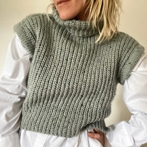 May include: A sage green knitted sleeveless sweater with a mock neck.