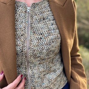 May include: A close-up of a brown crocheted top with a zip fastening. The top is worn over a blue denim shirt.