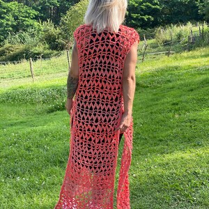 Pu&ograve; includere: Un lungo gilet in crochet color corallo con un delicato motivo a punto traforato. Il gilet ha una profonda scollatura a V e una silhouette lunga e fluida.