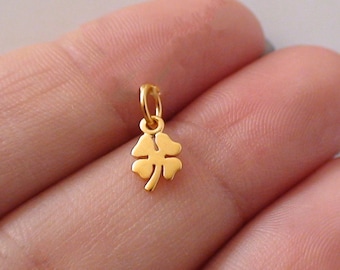 May include: A small gold four-leaf clover charm pendant.