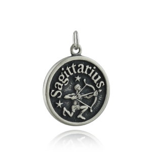May include: Silver charm pendant featuring the Sagittarius zodiac sign. The charm is round and has a black background with a silver image of a centaur holding a bow and arrow. The word "Sagittarius" is written around the edge of the charm.