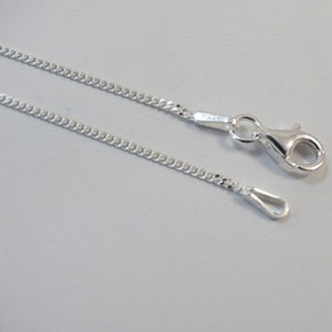 Puede incluir: Un collar de cadena de plata con un cierre de langosta y un anillo de salto. La cadena es de estilo curb.