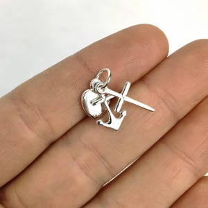 May include: Silver charm with a heart, anchor, and cross design. The charm is made of sterling silver and is perfect for adding a touch of faith and hope to any jewelry piece.